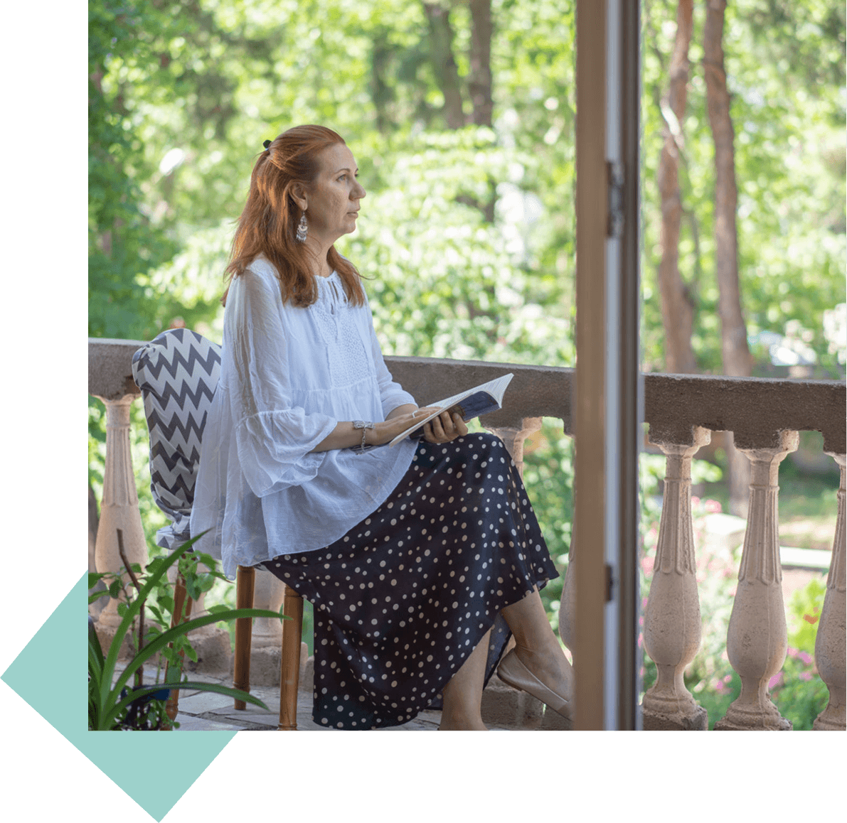 Woman reading book on a balcony.