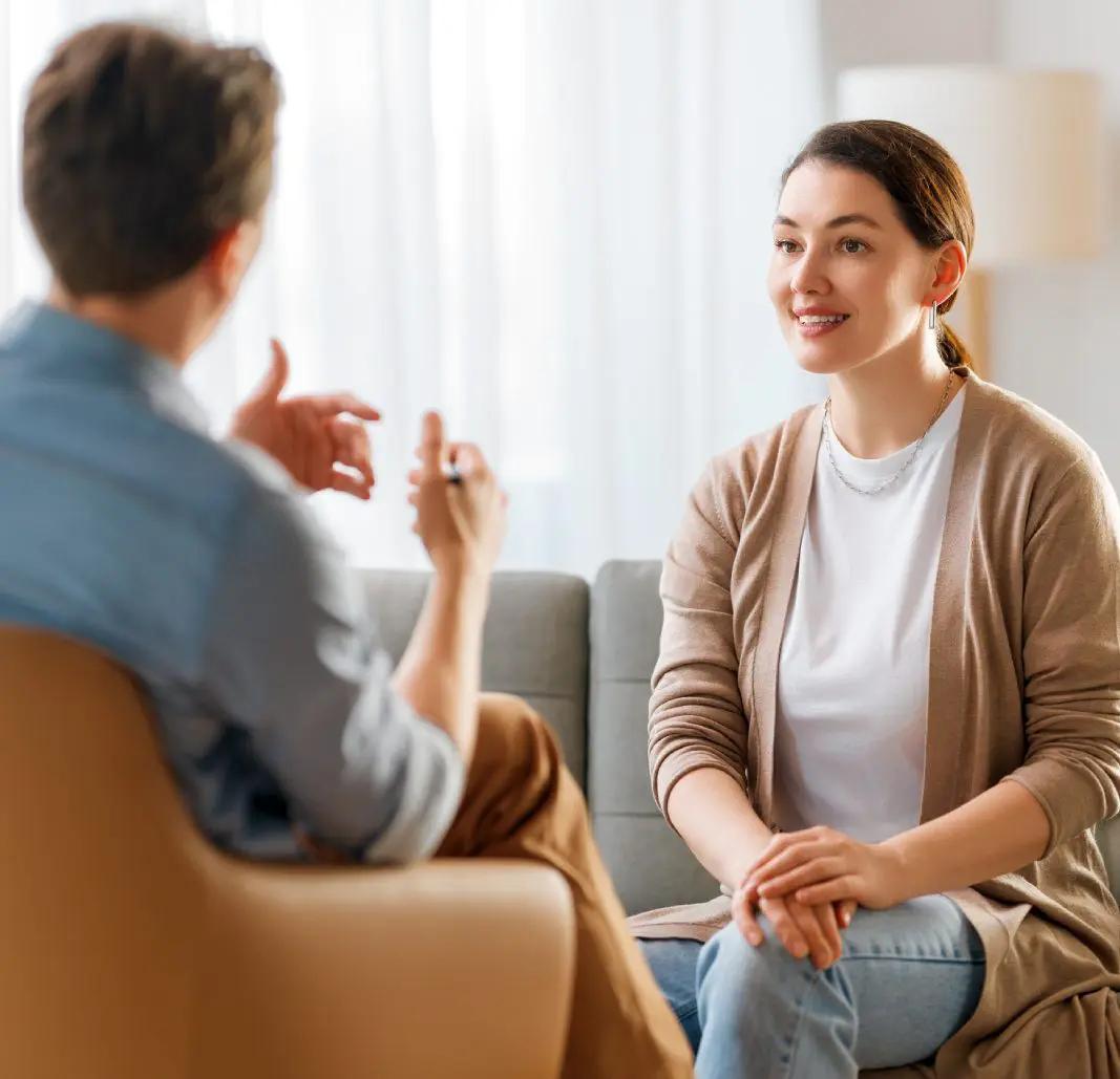 Two people talking on a couch.